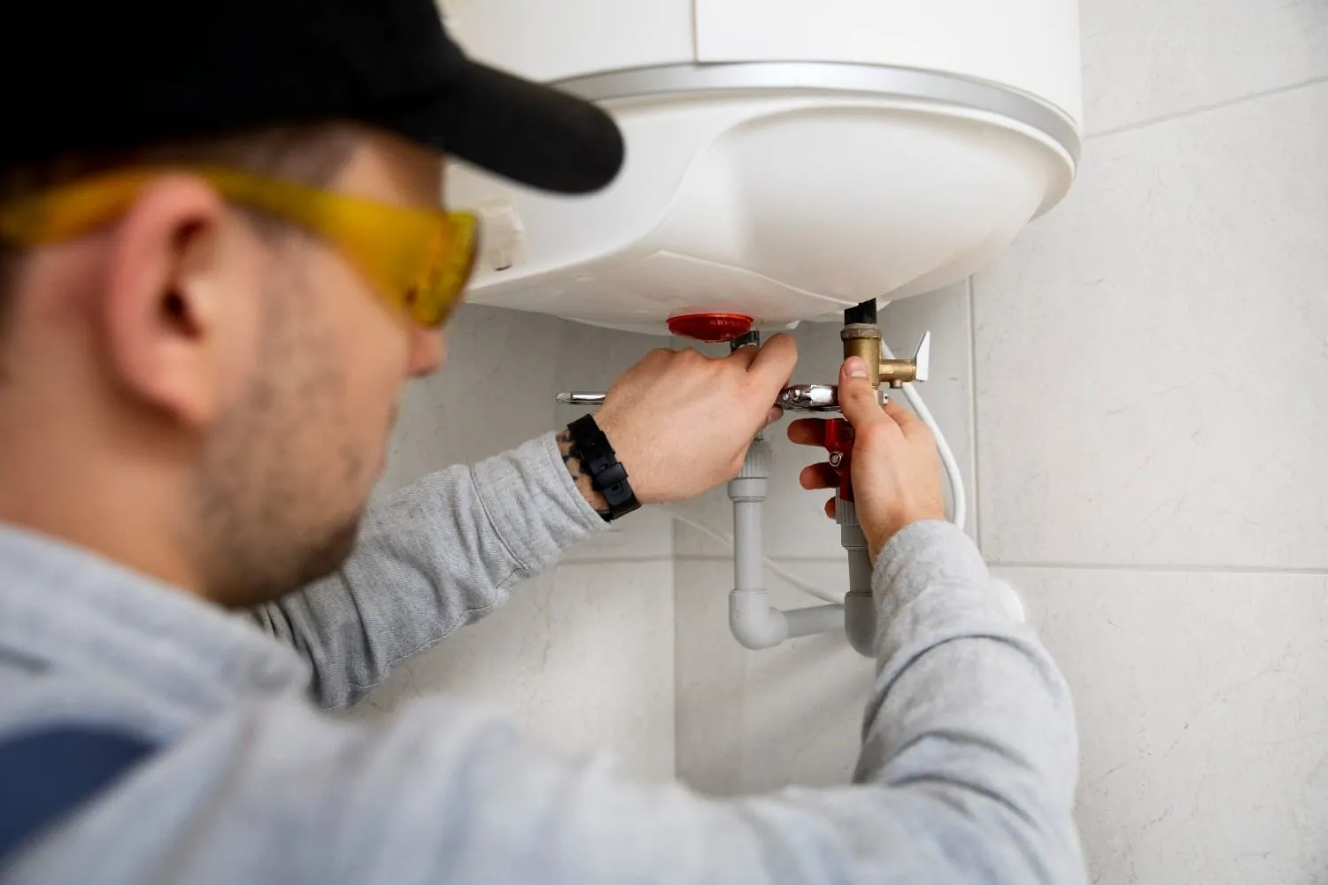 Technician adjusting the valves under a water heater